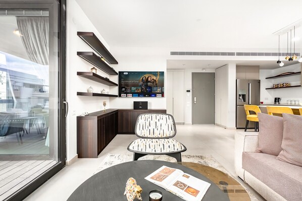 A modern living room with a TV, a dining area, and a kitchen.