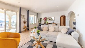 Un salon moderne avec un canapé, un fauteuil jaune et une table basse en verre.