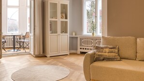 Tilava olohuone, jossa on beige sohva, valkoinen kaappi ja puinen kalanruotokuviollinen lattia.