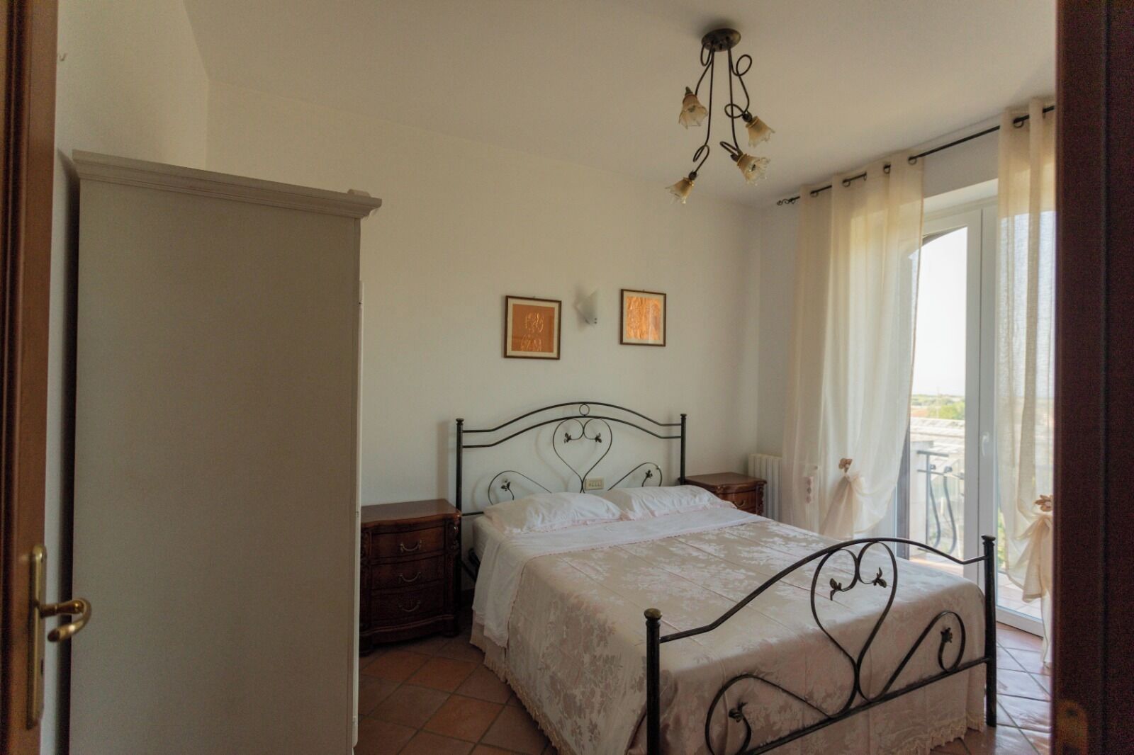 Une chambre à coucher avec un lit, une table de chevet, une commode et un lustre.
