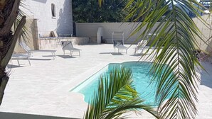 A swimming pool with a white deck, surrounded by palm trees and a grassy area. - La Mery Giò House (Fasano)