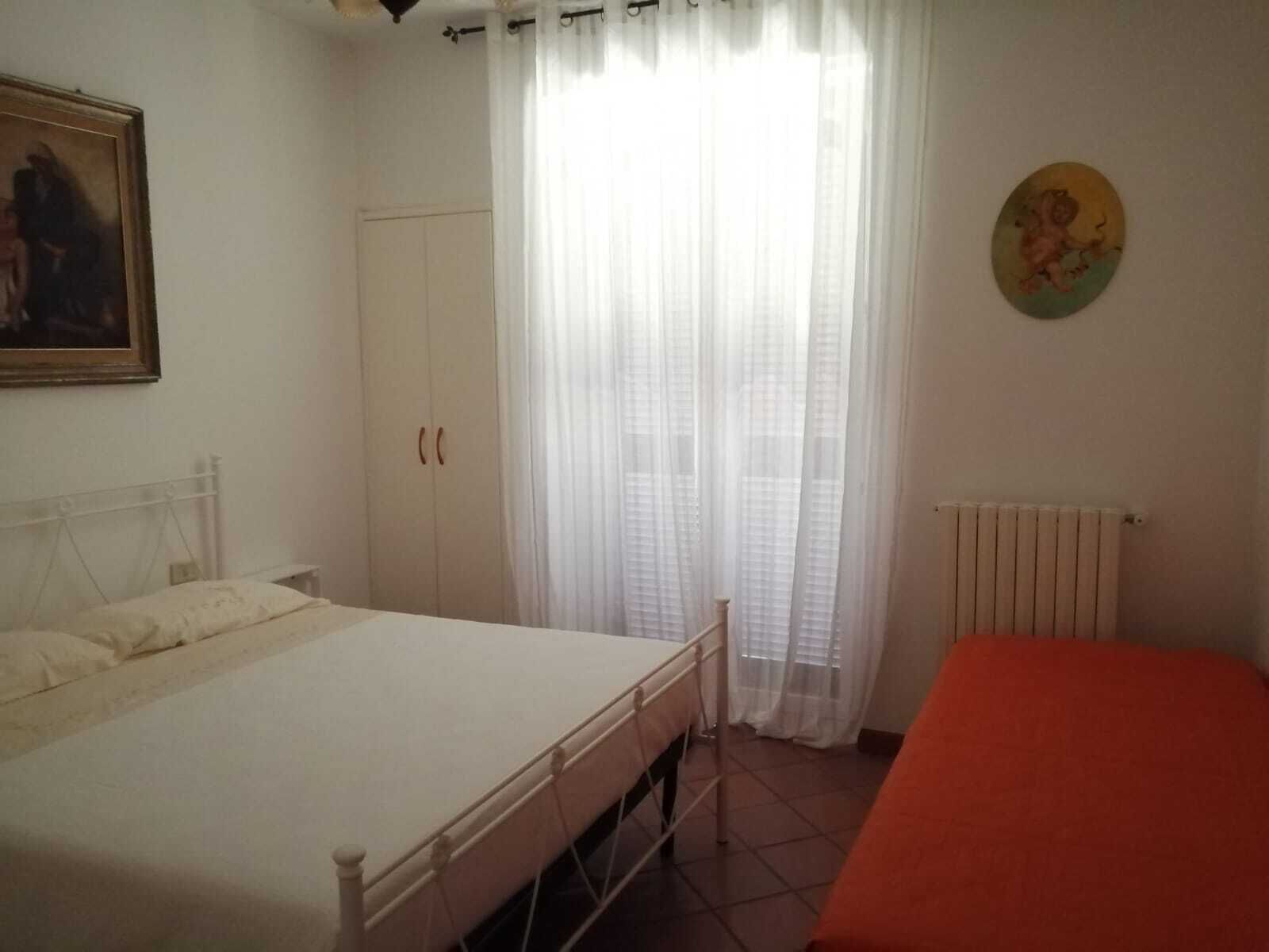 A bedroom with a bed, a wardrobe, a radiator, and a painting on the wall.
