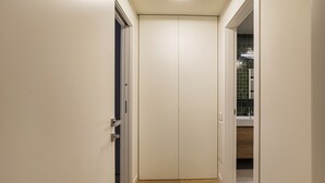 A hallway with a closed door, a visible bathroom with a tiled wall, and a wooden floor. - Waterfront Seaside in Genova (Genoa)
