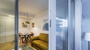 A modern living room with a green sofa, a dining table with chairs, and a glass partition. - Waterfront Seaside in Genova (Genoa)