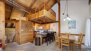 Een knus interieur van een chalet met een slaapverdieping, een keuken met moderne apparatuur en een eetgedeelte met houten meubels.