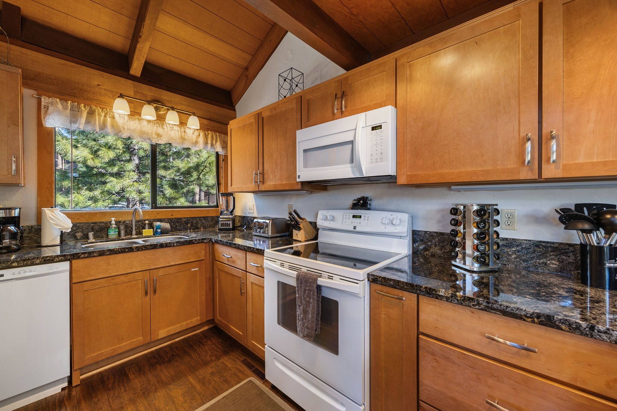 A kitchen with wooden cabinets, a microwave, a stove, and a coffee maker.