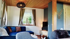 A cozy room with a wooden ceiling, a sofa with cushions, a television, and a deer head decoration on the wall. - Lovely apartment in villa for 6 guests with WIFI, pool, TV and terrace (Annaberg Im Lammertal)