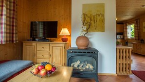 A cozy cabin interior with a wooden interior, a television, a fireplace, and a fruit bowl on a table. - Lovely apartment in villa for 6 guests with WIFI, pool, TV and terrace (Annaberg Im Lammertal)
