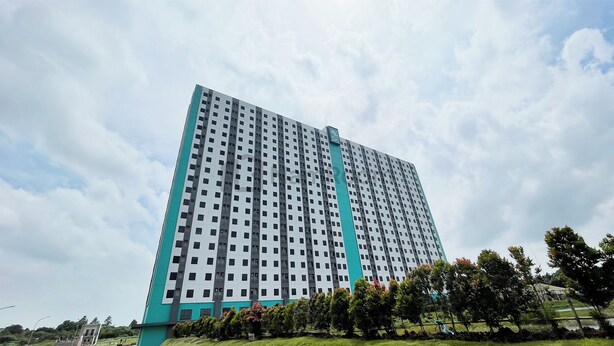 Un edificio moderno di grandi dimensioni, con un design architettonico caratterizzato da una griglia di finestre e una vistosa striscia verticale color verde acqua.