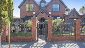 A large brick house with a symmetrical facade, a central entrance with a decorative gate, and a well-maintained front yard. - 6BR Lower Mitcham home, pool, cinema, near CBD (Lower Mitcham)