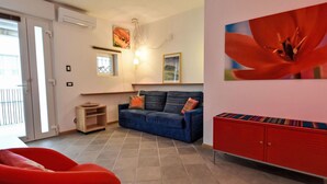 Ein Wohnzimmer mit einem blauen Sofa, einem roten Sessel und einem roten Schrank.