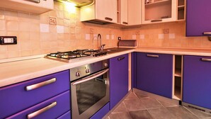 Eine Küche mit Gasherd, Backofen und violetten Schränken.