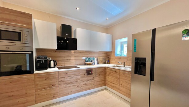 A modern kitchen with wooden cabinets, stainless steel appliances, and a tiled floor. - Kuća za odmor Fay (Crikvenica)
