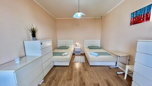 A compact bedroom with two beds, a bedside table, a small desk, a potted plant, and a ceiling light. - Kuća za odmor Fay (Crikvenica)