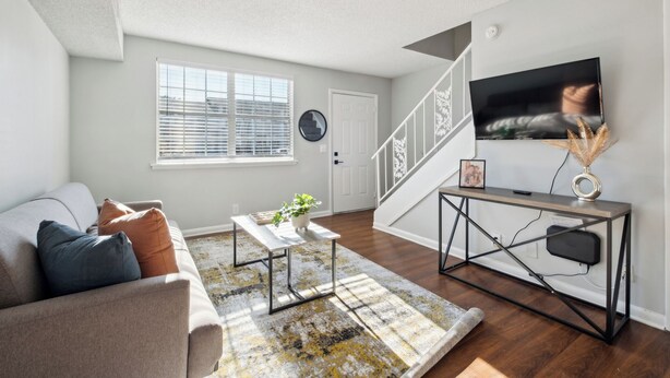 A modern living room with a sofa, coffee table, and a staircase leading to another level.