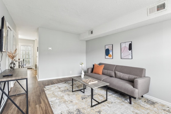 A modern living room with a grey sofa, a coffee table, and a rug.