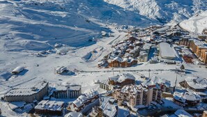A snow-covered mountain town with ski slopes and buildings. - Cozy apartment at the slopes with balcony (Val Thorens)