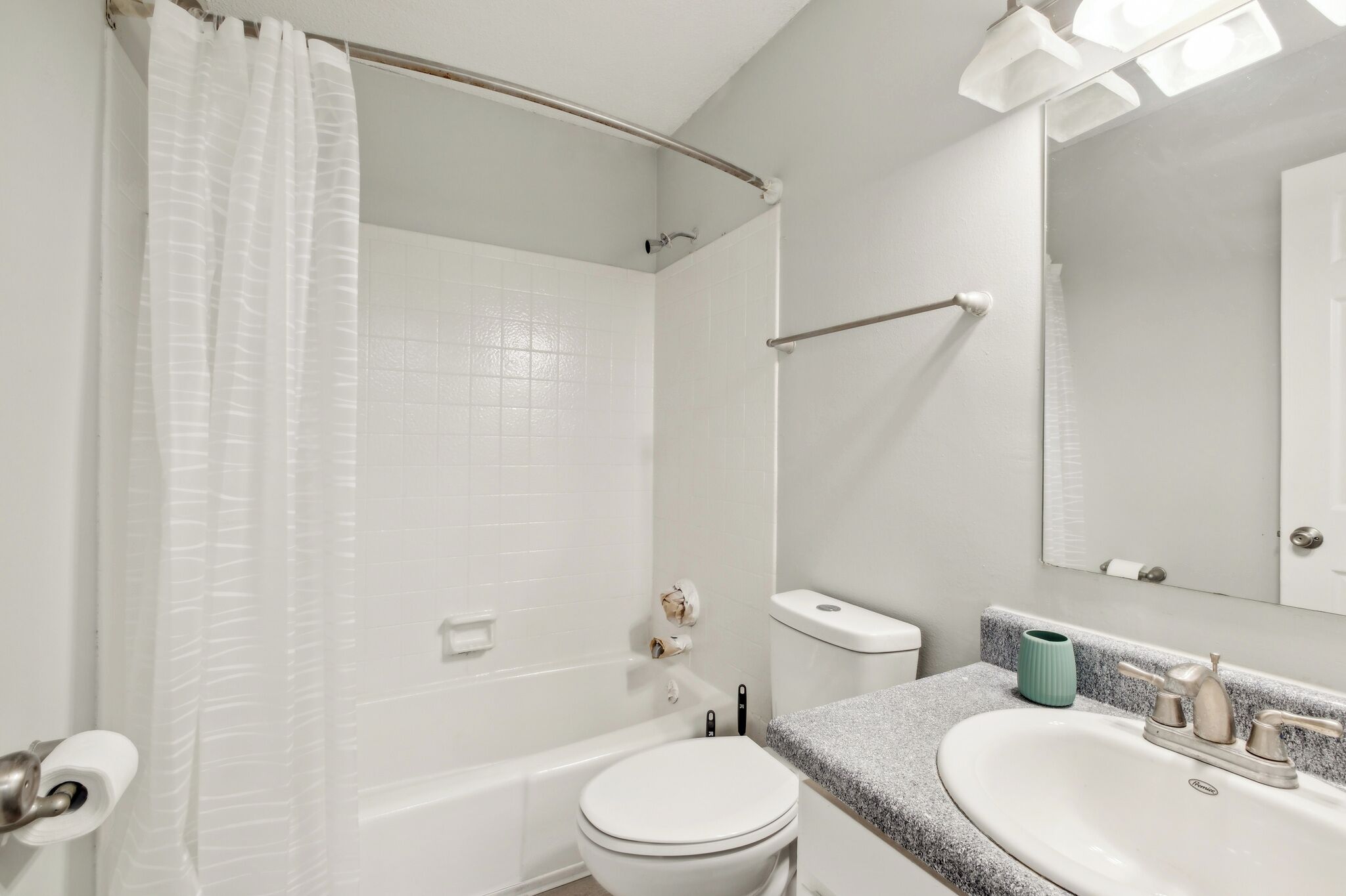 A bathroom with a bathtub, toilet, sink, and a mirror.