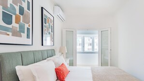A neatly arranged bedroom with a bed, pillows, a lamp, and artwork on the wall. - Seaside Modern Flat II at Cascais (Cascais)