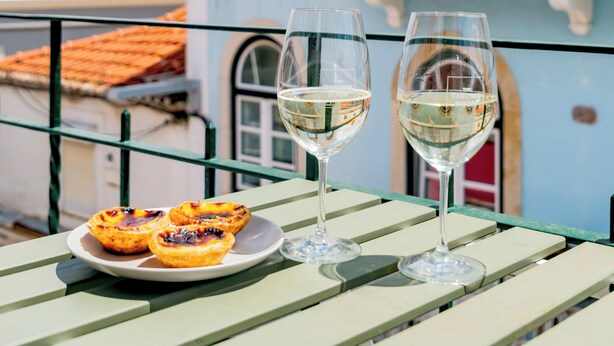 A table with two glasses of white wine and a plate of food on a balcony. - Seaside Modern Flat II at Cascais (Cascais)