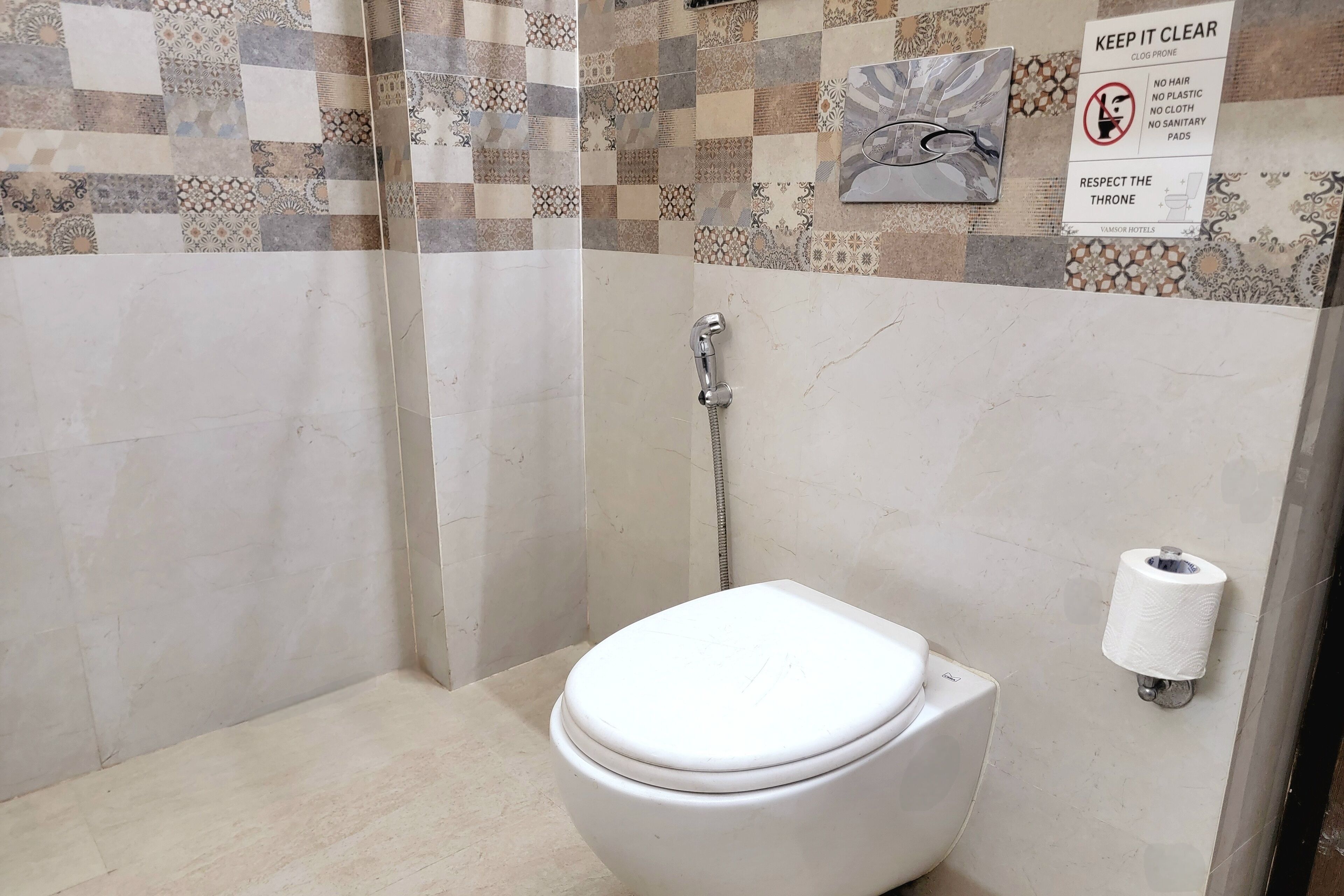 A bathroom with a white toilet, a shower, and a patterned wall. A sign on the wall states "KEEP IT CLEAR" and "RESPECT THE THRONE."
