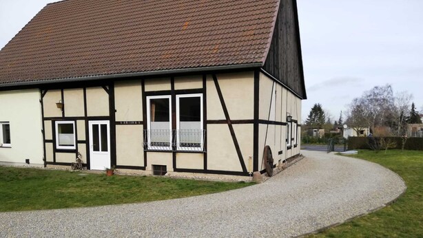 Ein traditionelles Fachwerkhäuschen mit Kiesweg und kleinem Garten.