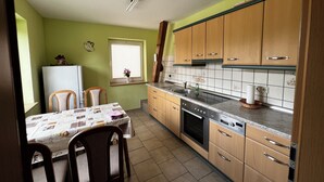 Eine kompakte Küche mit Holzschränken, einem eingebauten Backofen und einem Essbereich mit zwei Stühlen und einem Tisch.