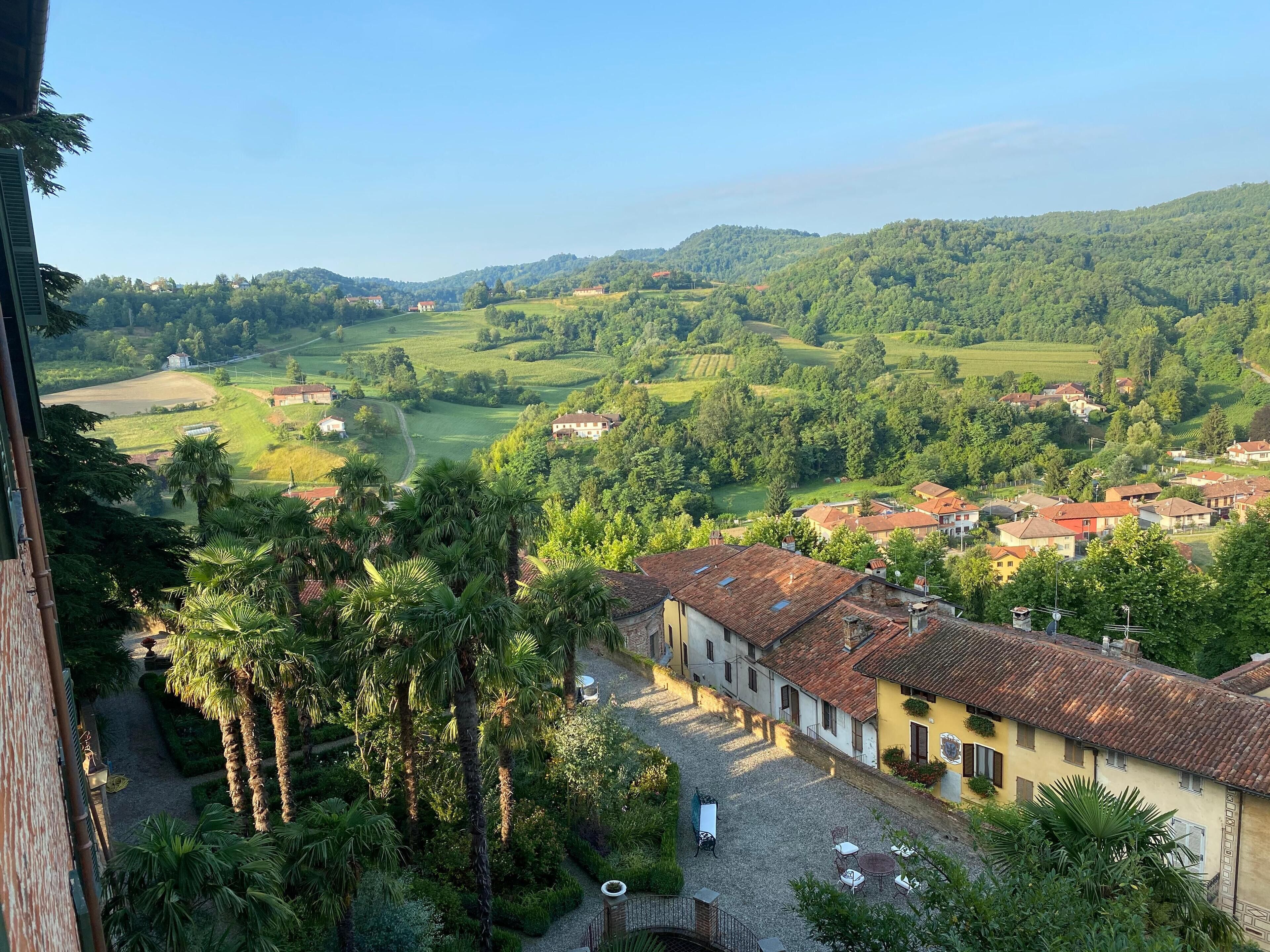 A villa with a courtyard, surrounded by lush greenery and hills.