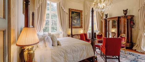 Un dormitorio lujoso con una cama grande, una araña ornamentada y decoración clásica.