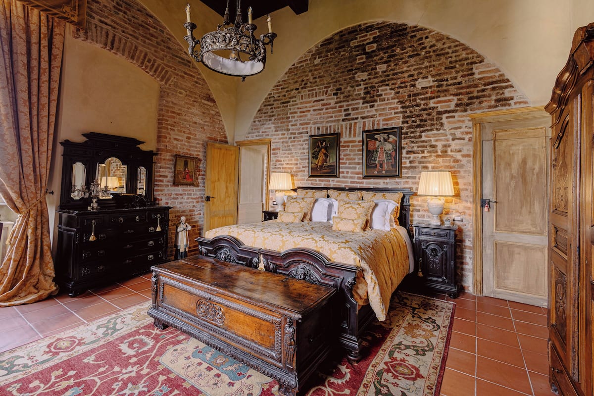 Ein Schlafzimmer mit Backsteinwand, einem hölzernen Bett, einem Schminktisch und einer Chandelier.