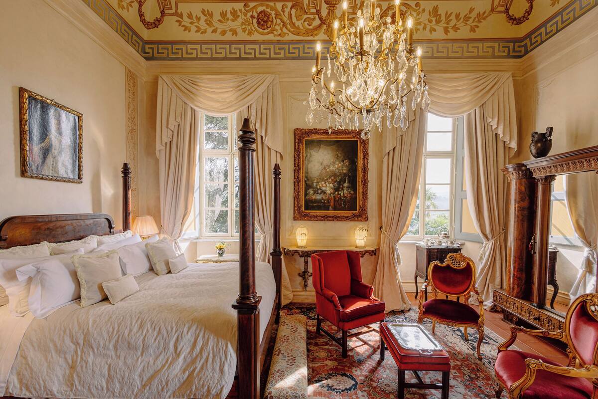 Ein luxuriöses Schlafzimmer mit einem Himmelbett, einer Chandelieber und klassischer Einrichtung.