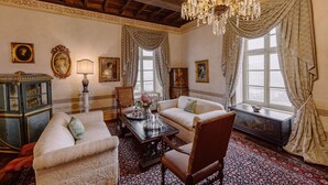 A room with a chandelier, two sofas, a table with a vase, and a cabinet. - Castello di Casalborgone - Luxury Castle (Casalborgone)