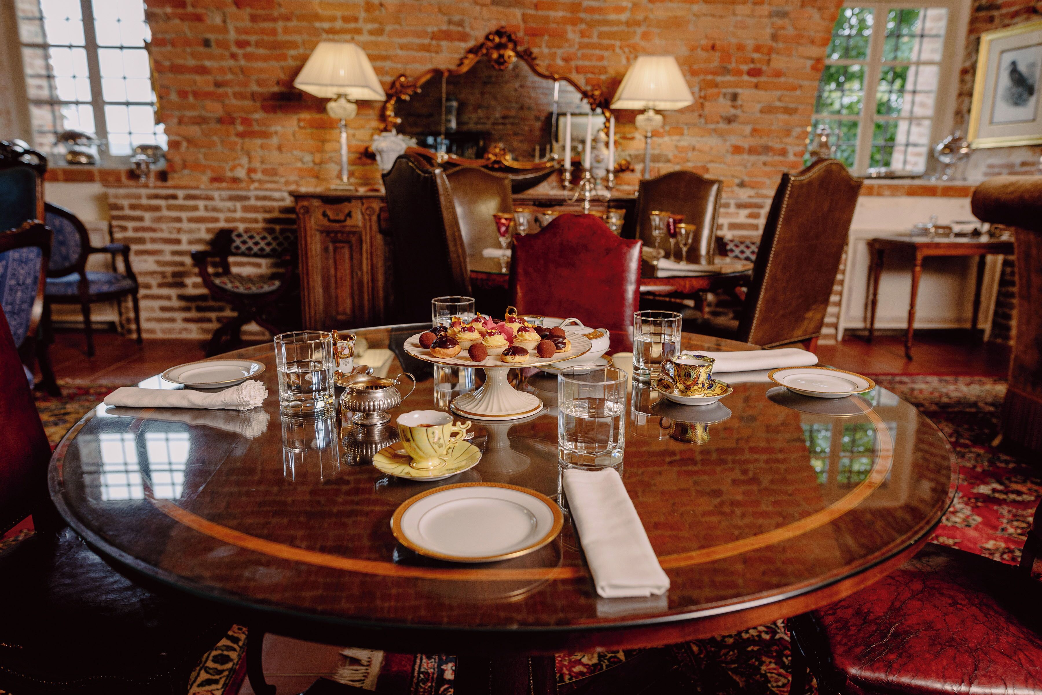 A dining table set with plates, glasses, and a variety of desserts.
