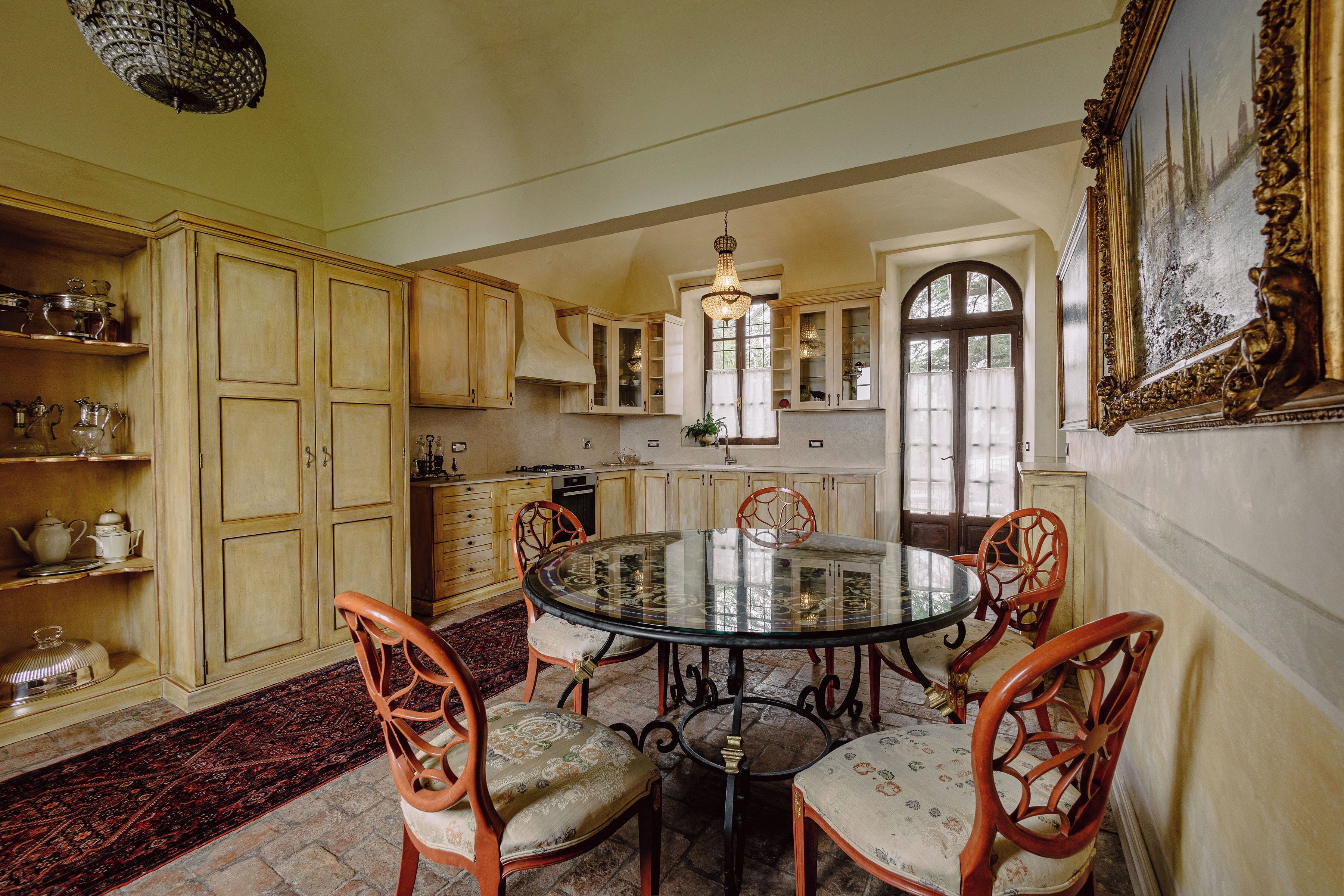 Een eetgedeelte met een ronde glazen tafel, omringd door houten stoelen met comfortabele zitkussens.