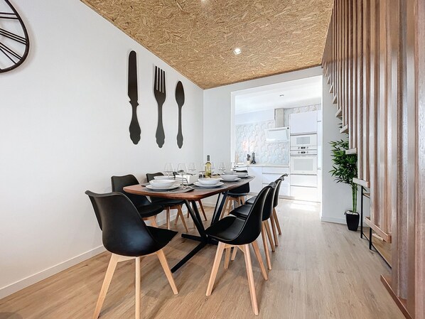 A modern dining area with a wooden ceiling, black chairs, and a white table set for four.