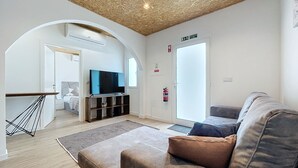 Uma sala de estar moderna com televisão de tela plana, um sofá, uma mesa de centro e teto de madeira.