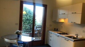 Uma cozinha compacta com área de refeições, varanda com vista para vegetação e uma pequena mesa de jantar com cadeiras.