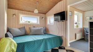 Um quarto acolhedor com uma cama, uma televisão e uma janela.