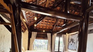 A rustic bedroom with a wooden ceiling, a bed, a bench, and a view of the outside. - The Monhi Da Lat (Xuan Huong - Da Lat)