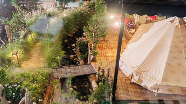 A tented area with a wooden deck, surrounded by lush greenery and a small stream. - The Monhi Da Lat (Xuan Huong - Da Lat)