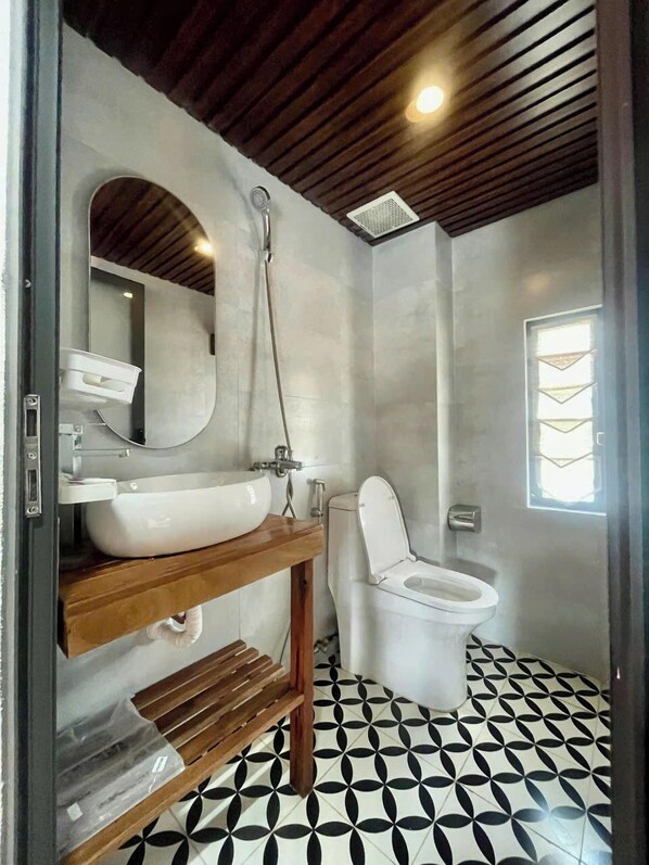Un baño con tocador de madera, lavamanos blanco, inodoro y ducha.