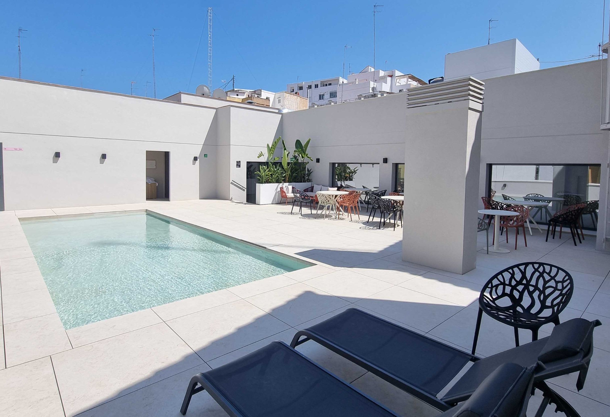 Une piscine sur le toit, d’une profondeur de 40 cm, entourée d’espaces de détente en plein air et intégrée dans un cadre architectural moderne.