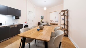 A modern kitchen with a wooden dining table, chairs, and a built-in oven.