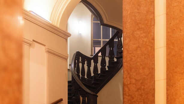 A grand staircase with marble walls and a wooden handrail.