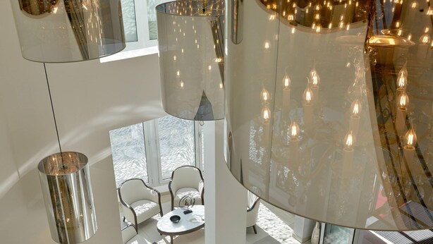 Un intérieur moderne avec un plafond haut, des surfaces réfléchissantes et un espace salon doté d’une table ronde.