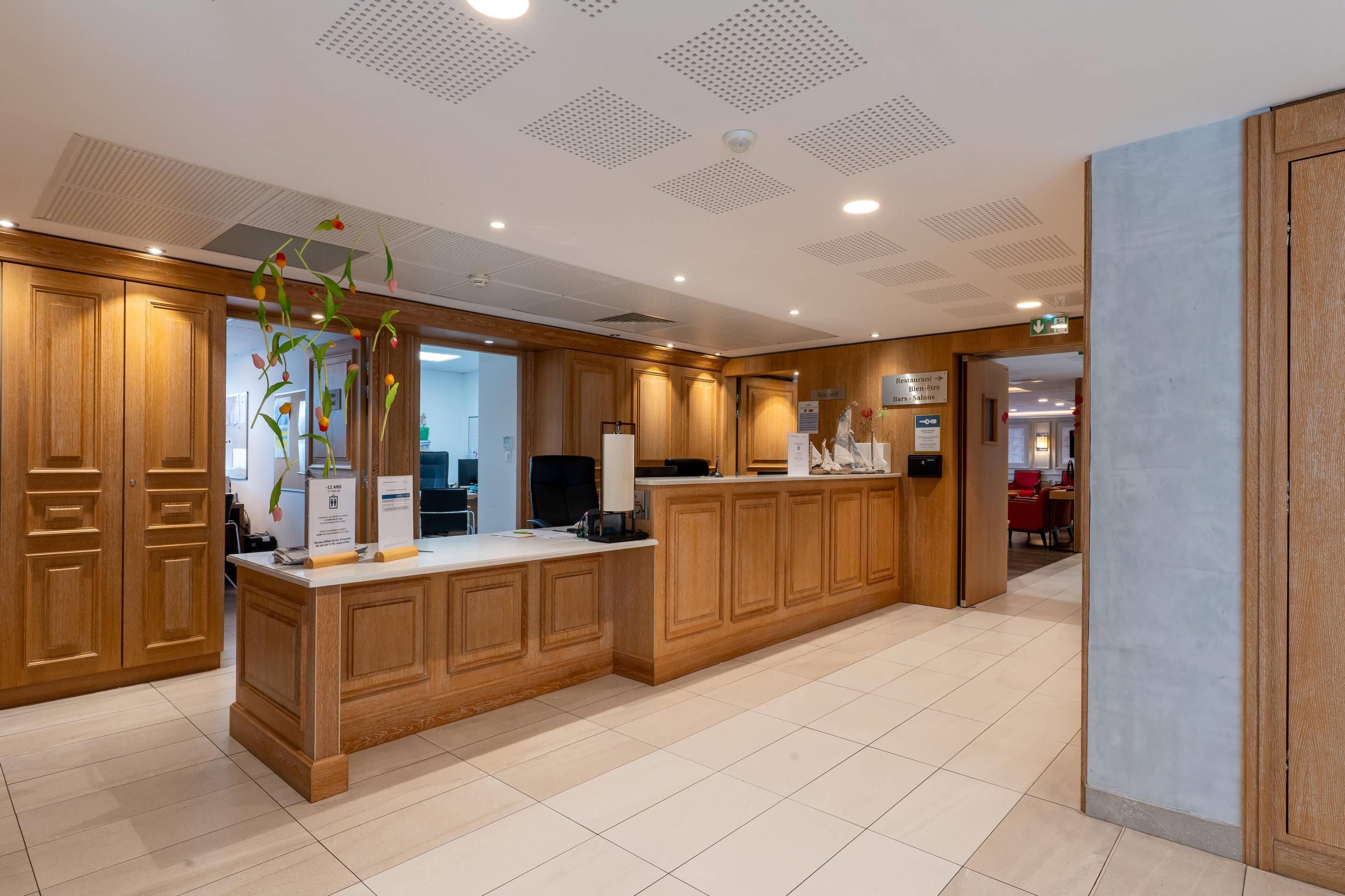 A modern kitchen with wooden cabinetry, a central island, and a view into the dining area.