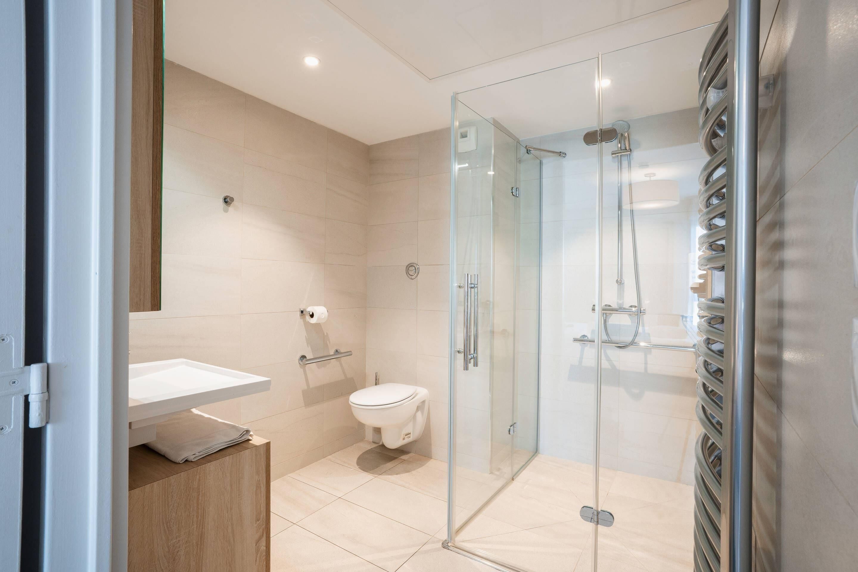 A modern bathroom with a glass-enclosed shower, a toilet, and a sink.