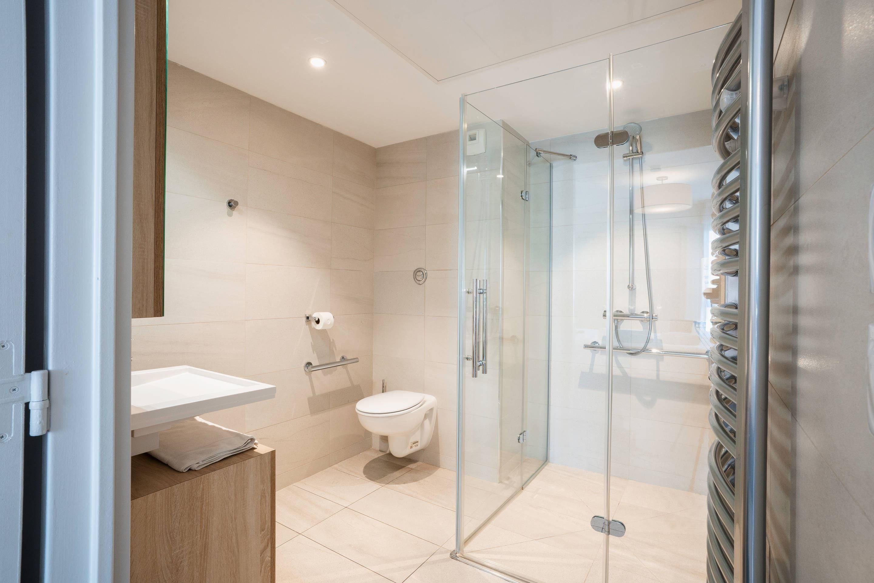 A modern bathroom with a glass-enclosed shower, a toilet, and a sink.
