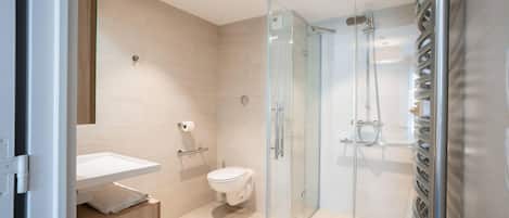 A modern bathroom with a glass-enclosed shower, a toilet, and a sink.