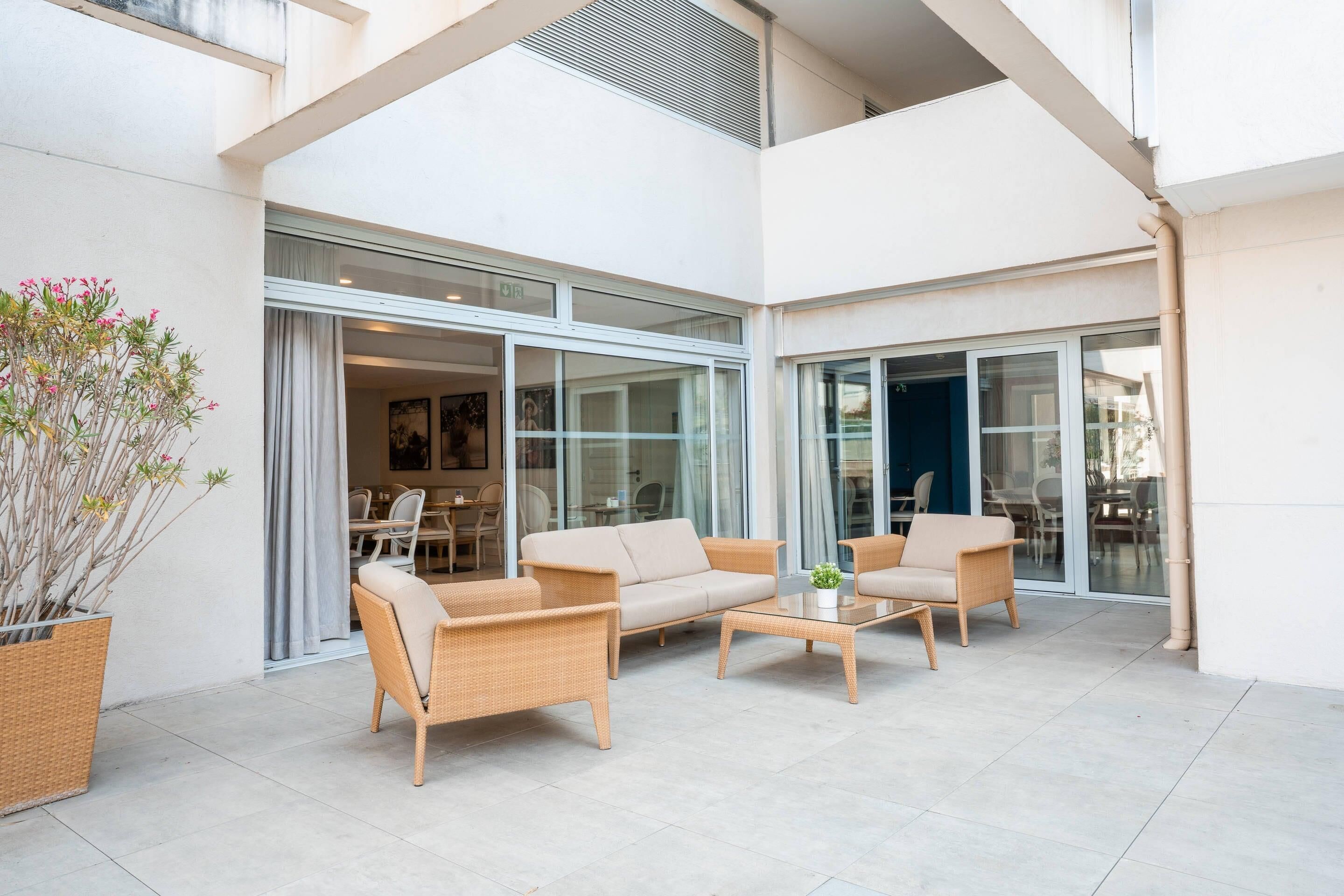 A spacious outdoor seating area with wicker furniture, a glass door entrance, and a potted plant.